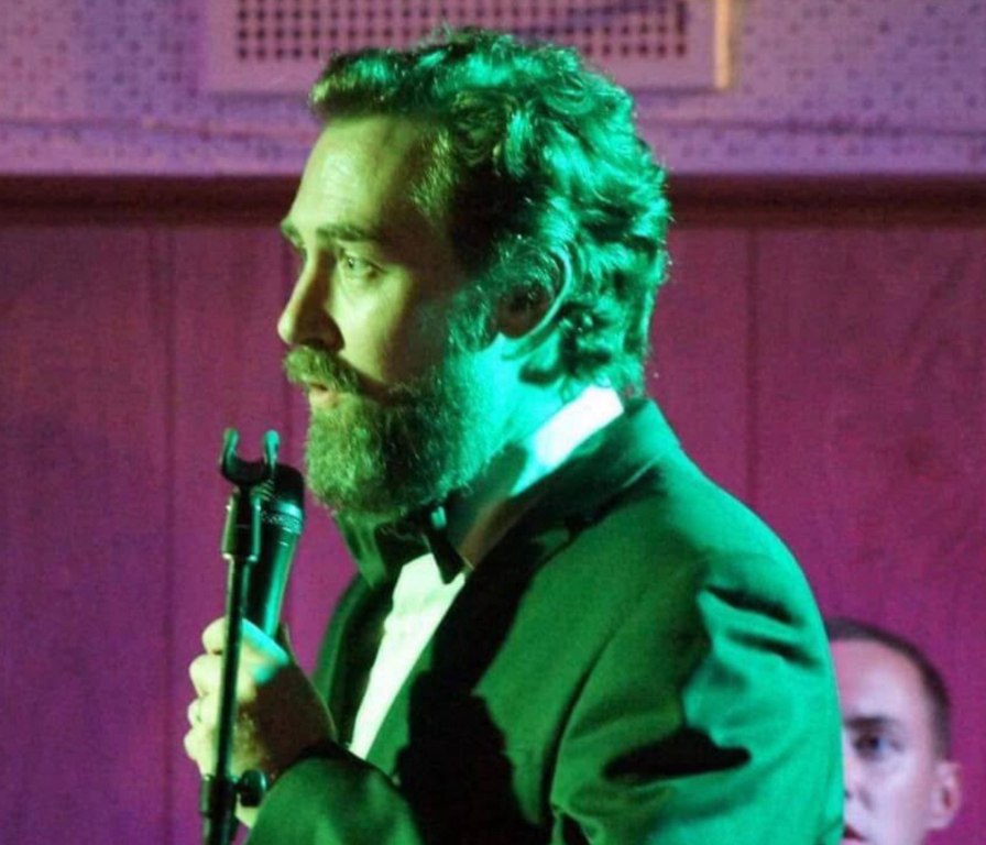 Wade Morgan Melbourne Jazz Singer performing on stage with microphone, wearing elegant attire with dramatic stage lighting