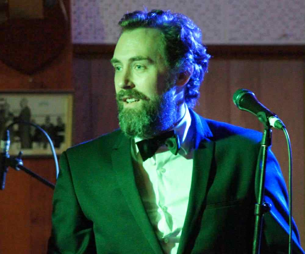 Wade Morgan performing in an elegant green suit with stage lighting